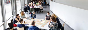 Personen sitzen an Tischgruppen