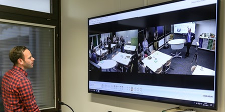 Person steht vor großem Bildschirm mit Kameras