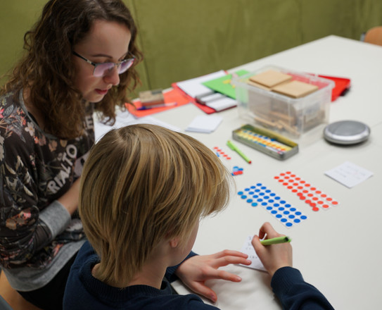 Studierende sitz mit Schüler an Tisch
