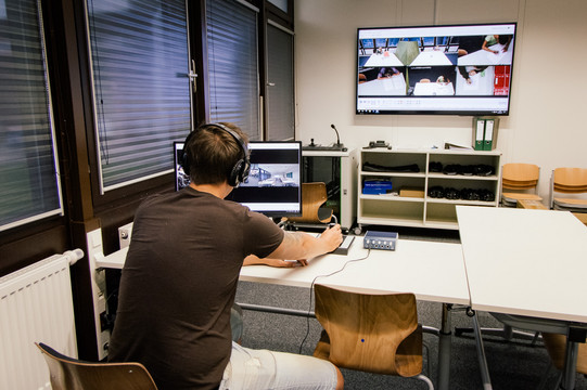 Studierender sitzt vor Bildschirm und beobachtet Videoaufzeichnungen