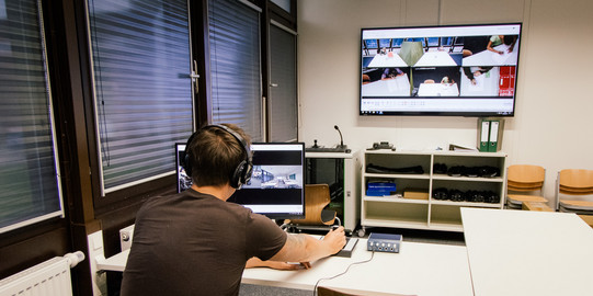 Studierender sitzt vor Bildschirm und beobachtet Videoaufzeichnungen