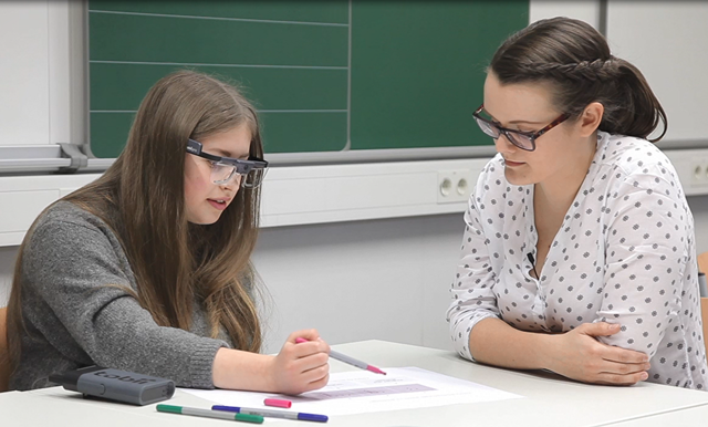 Zwei Personen sitzen mit Eyetrackingbrillen an einem Tisch
